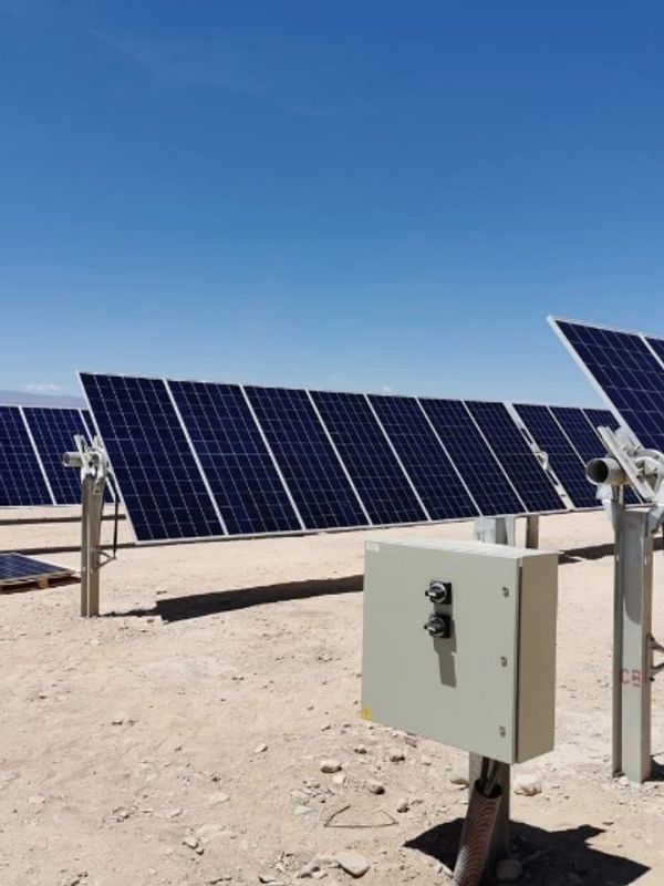 Solar panels installed in a desert under clear blue skies.