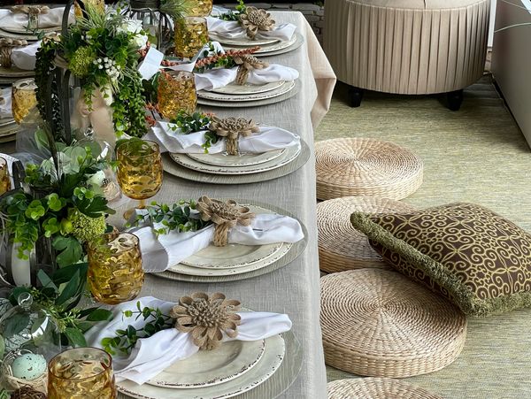Low table with ivory place settings, greenery garlands and floor cushions.