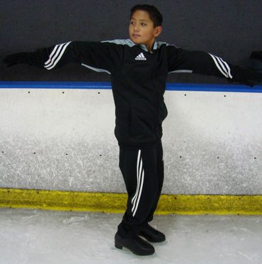 an ice skater demonstrates a skating position
