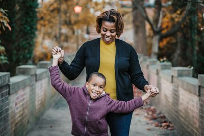 Mother and child, smiling and holding hands.