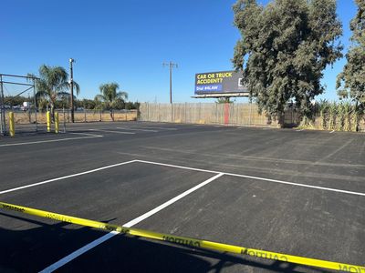 An empty parking lot with caution tape and a billboard in the background.