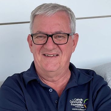 Smiling elderly man in glasses and navy polo shirt.