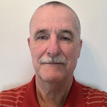 Portrait of an older man with a mustache wearing a red polo shirt.