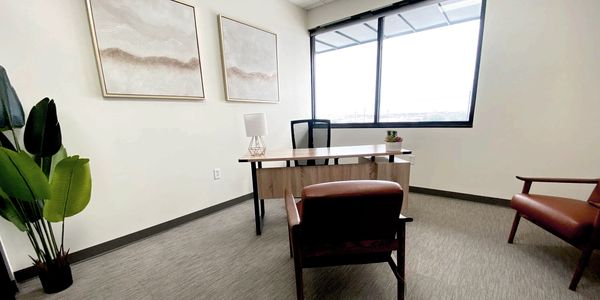 A minimalist office with a wooden desk, chairs, and large window.