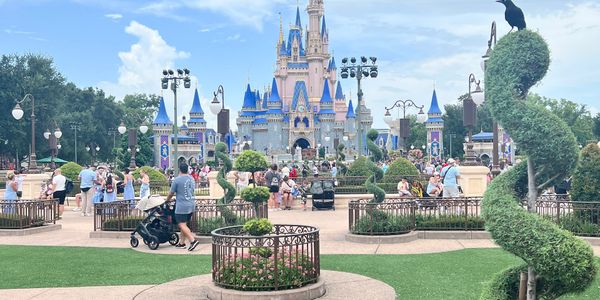 Cinderella Castle at Disney World with visitors and manicured gardens on a bright day.