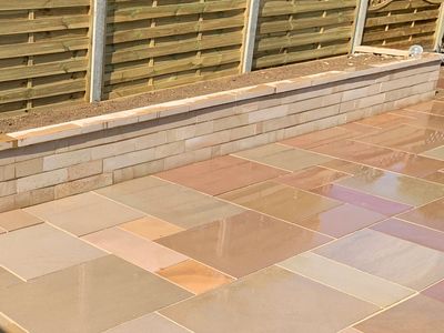 Patio created using Fernshaw Natural Sandstone slabs and wall built to create a raised flower bed