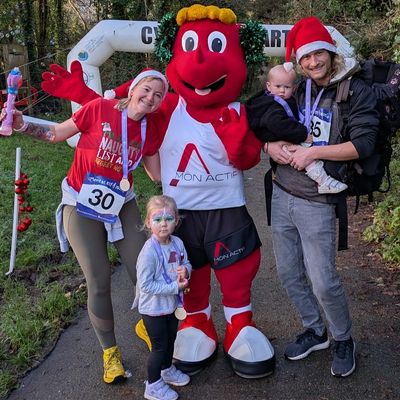 Family posing with a mascot at a fun run event.