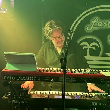 Chris Runnels playing keyboard on stage under green light.