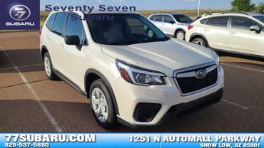 White Subaru SUV parked in a dealership lot.