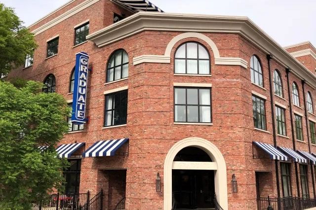 Brick building with a vertical Graduate sign and striped awnings.