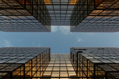 View looking up at tall, reflective glass skyscrapers against a blue sky.