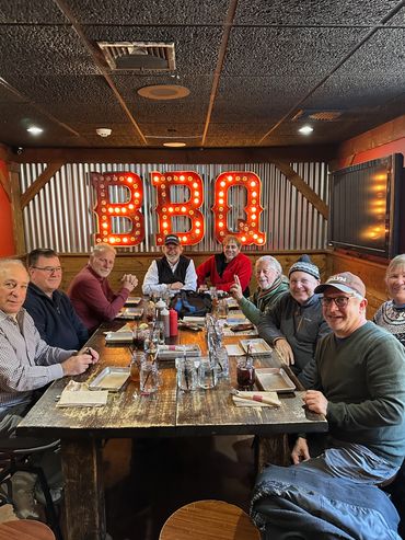 Group of eight people enjoying a meal together at a BBQ restaurant.