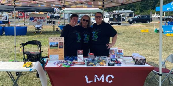 Three people at LMC booth at outdoor event