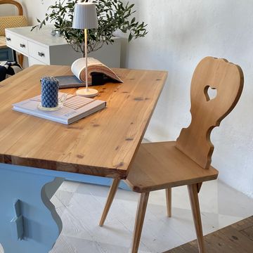 Cozy wooden chair and table setup with decorative candle and lamp.