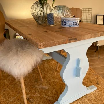 Cozy wooden table with decorative items and a fluffy chair seat.