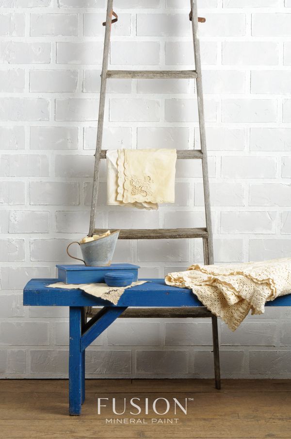 Rustic interior setup with a blue bench, vintage ladder, and crochet fabrics.
