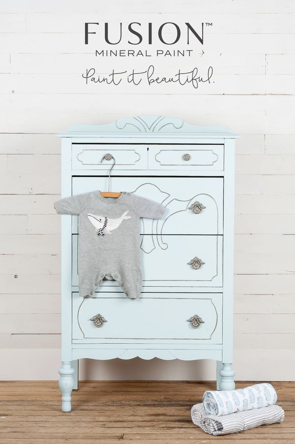 Light blue painted vintage dresser with baby clothes and blankets.