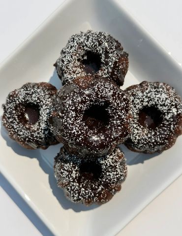 Chocolate mini bundt cakes dusted with powdered sugar on a white plate.