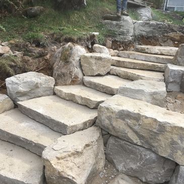 Stone steps under construction with large rocks and dirt around.