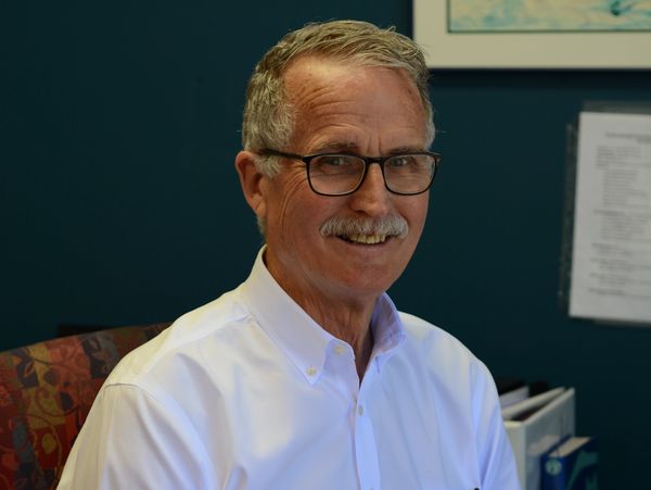 Picture of Doctor Paxton: an older man with a white shirt and a grey mustache smiling.