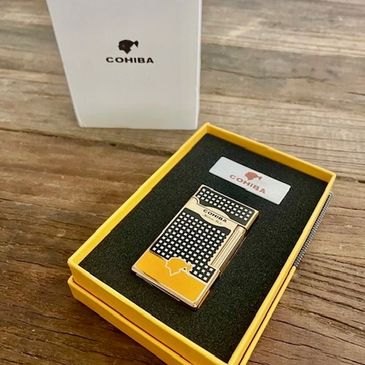 A luxury Cohiba lighter in a yellow box on a wooden surface.