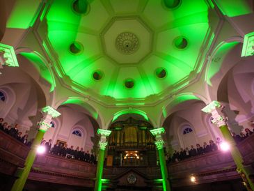 Interior view of a dome lit with green lights and people gathered around.