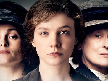 Three women with serious expressions, dressed in early 20th-century attire.
