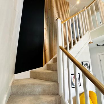 Carpeted staircase with wooden handrails and modern vertical wood paneling.