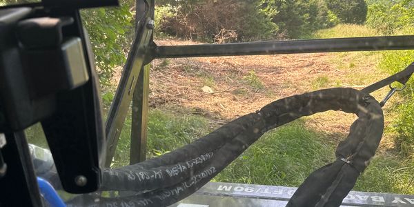 View through a vehicle's windshield showing a tow strap and a grassy path.