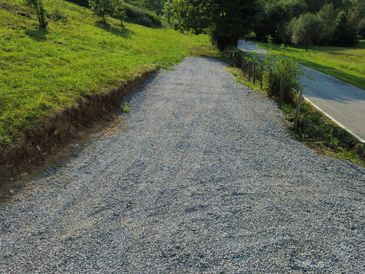 Newly laid gravel path beside a paved road in a green countryside.