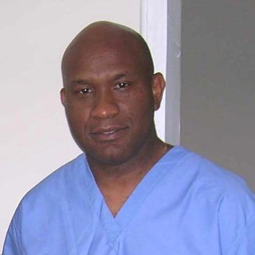 Portrait of a man in blue medical scrubs.