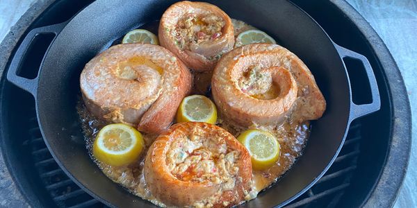 Fish steaks cooking in a pan with lemon slices.