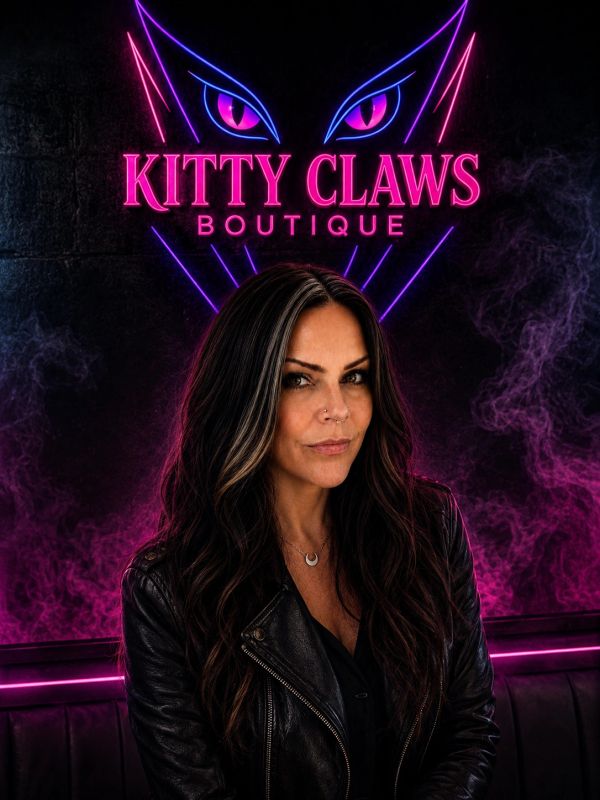 Woman in leather jacket under neon Kitty Claws Boutique sign.