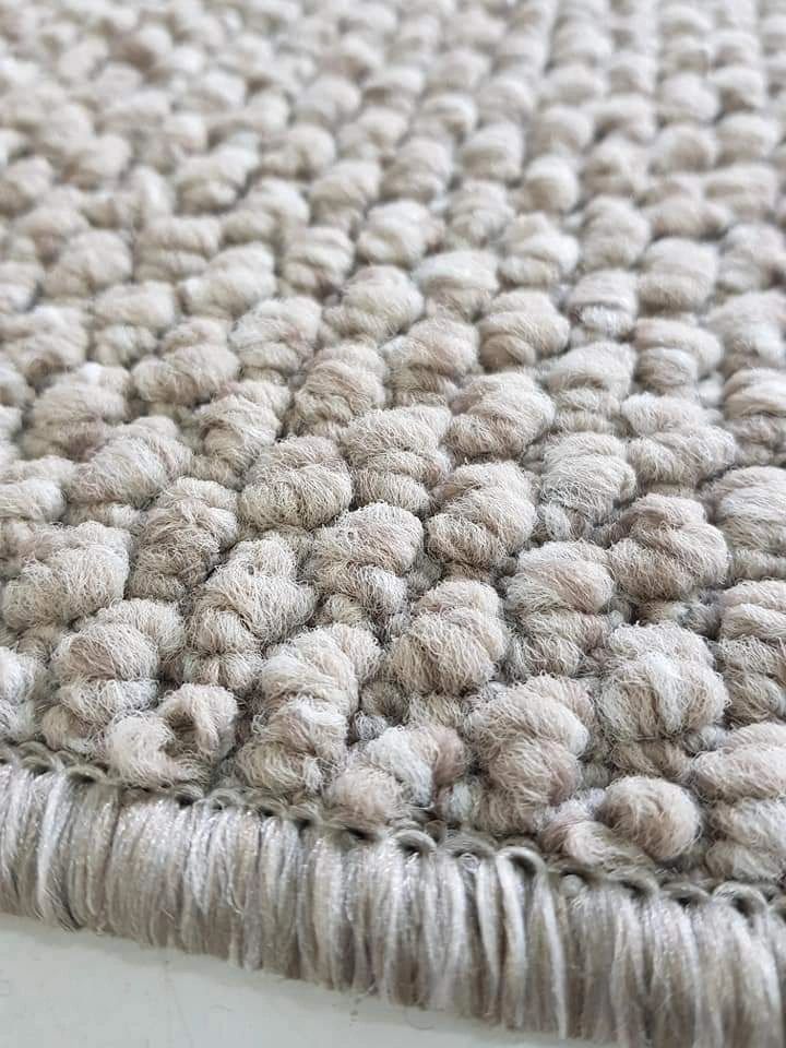 Close-up of a textured, looped beige carpet edge.