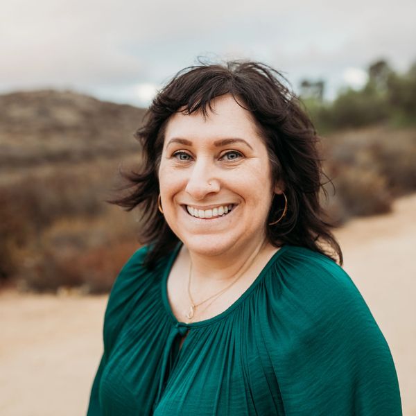 Photographic headshot of Emily Beltran standing outside smiling 