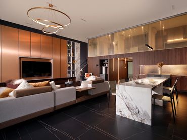 Modern living room and kitchen with elegant marble island and warm lighting.