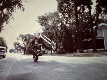 Man performing a motorcycle wheelie on a suburban street.