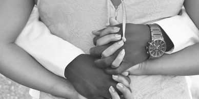 Couple holding hands closely, symbolizing unity and love.