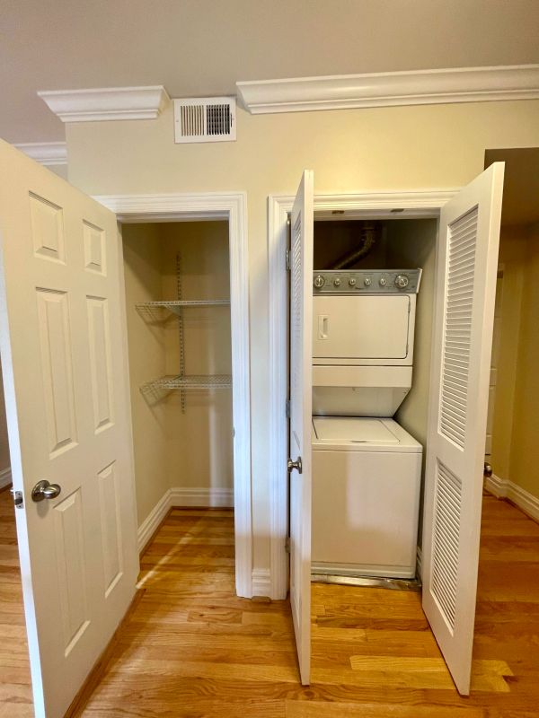 Open closets showing an empty shelving closet and a stacked washer and dryer unit.