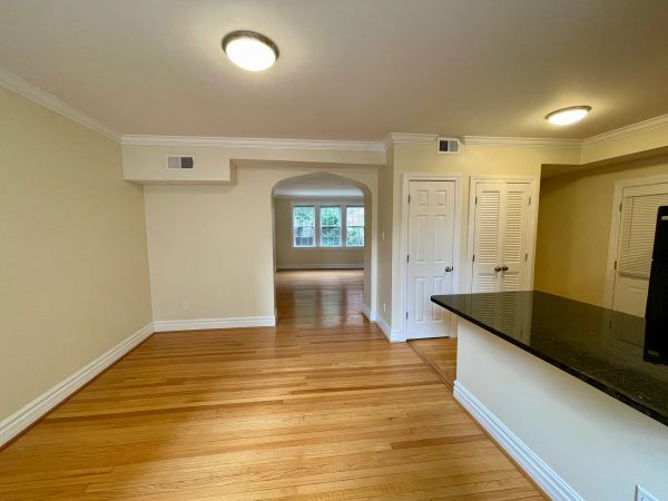 Empty room with wooden floors, beige walls, and black granite countertop.