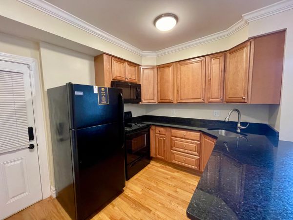 Modern kitchen with wooden cabinets and black appliances.