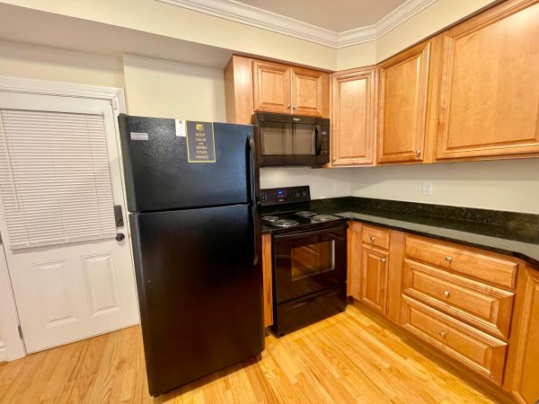 Compact kitchen with black appliances and wooden cabinets.