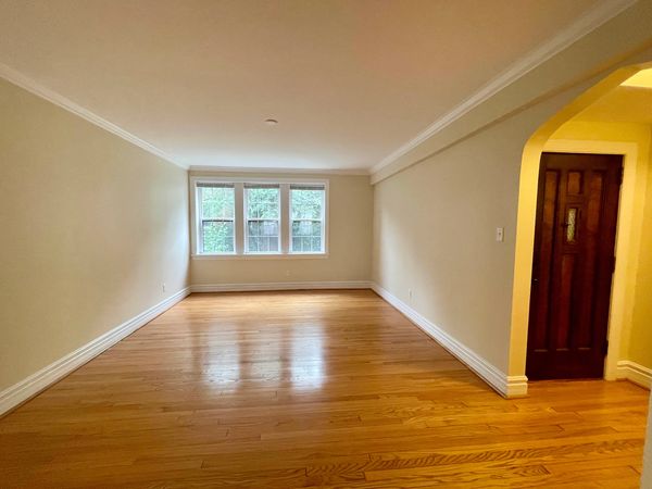 Empty room with wooden floors and a window at the far end.