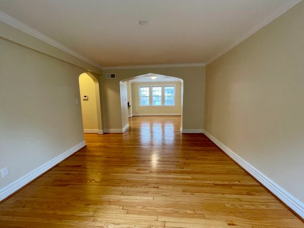 Empty room with wooden flooring and beige walls.