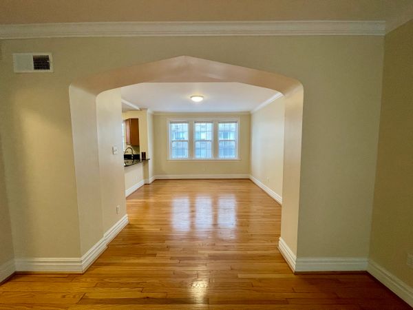 Empty room with wooden floor and arched entryway.