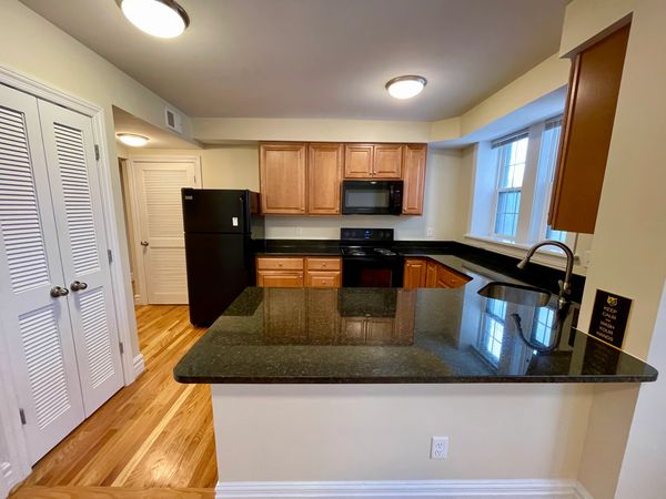 Modern kitchen with black appliances and granite countertops.