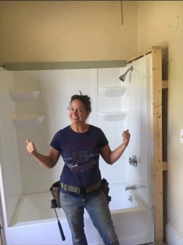 Woman standing happily in front of a new bathtub and shower.