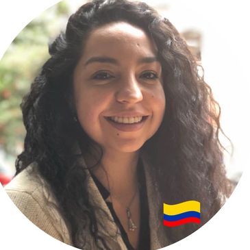 Smiling woman with curly hair and Colombian flag icon.