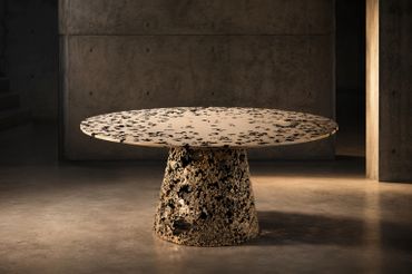 Round table with a unique textured base and top in a dimly lit modern room.