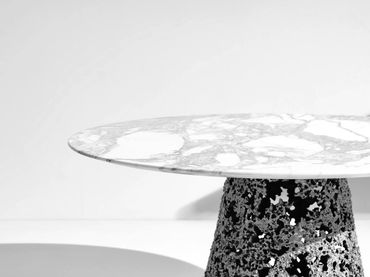 Modern round table with a marble top and an intricate black base.